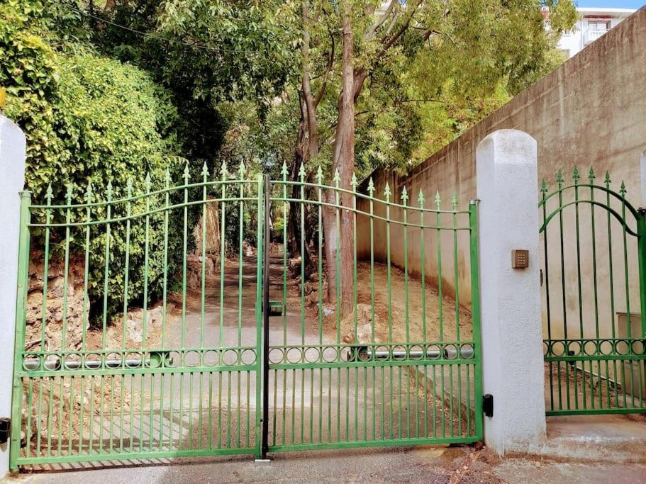 a green metal gate in front of a fence at Appartement de 55m2 climatisé à 6 min du tram in Marseille