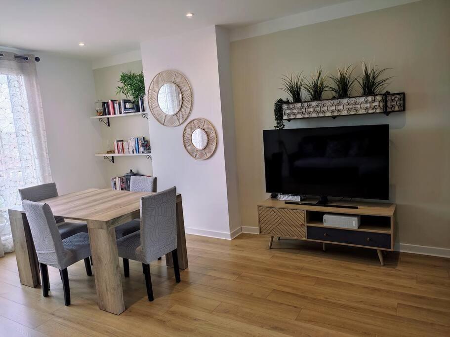 a living room with a wooden table and a television at Appartement de 55m2 climatisé à 6 min du tram in Marseille