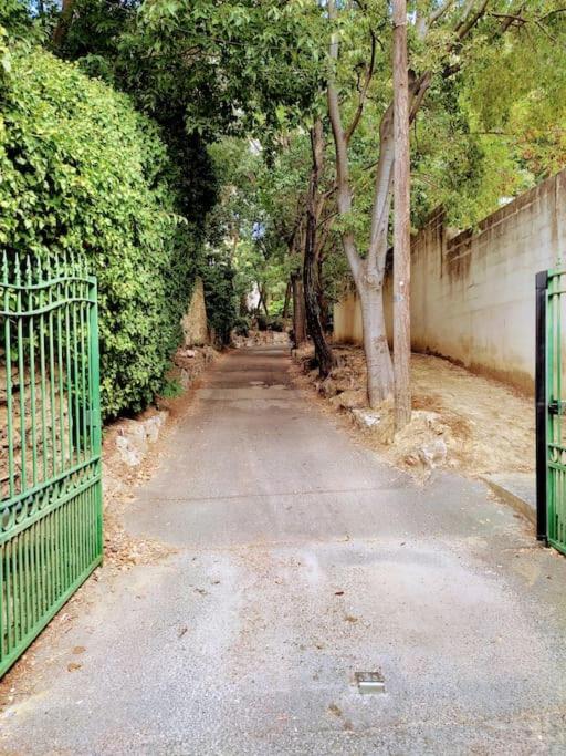 an empty road with a green fence and trees at Appartement de 55m2 climatisé à 6 min du tram in Marseille