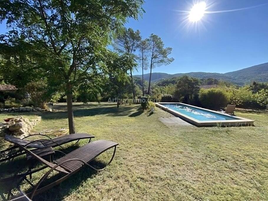 a swimming pool with two chairs in a yard at Splendide villa 10p./4 suites/piscine/clim/paysage in Bargemon