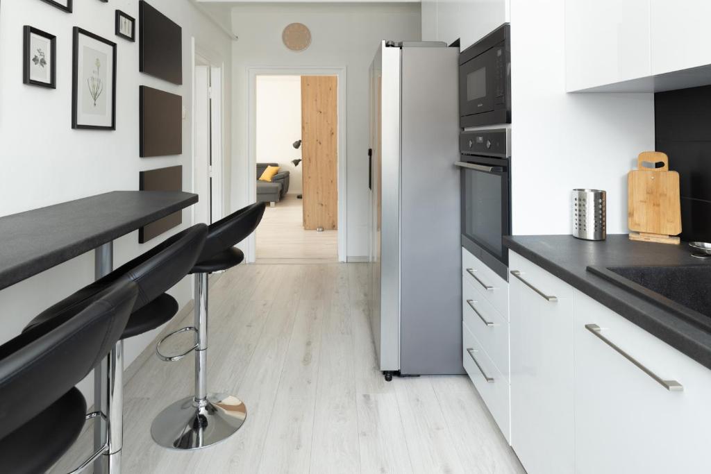 uma cozinha com armários brancos e bancadas pretas em Smart Square with free parking em Debrecen
