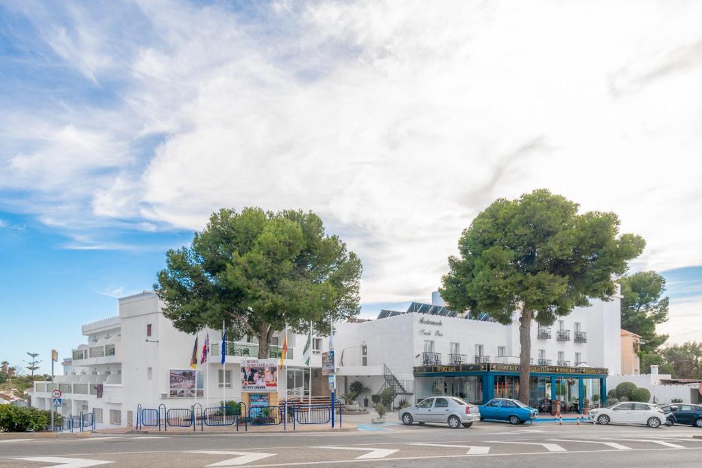 ein weißes Gebäude mit Autos auf einem Parkplatz in der Unterkunft Hotel Nerja Club Spa by Dorobe in Nerja