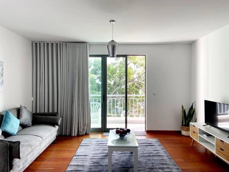 uma sala de estar com um sofá e uma grande janela em Ocean Pearl Apartment X no Funchal