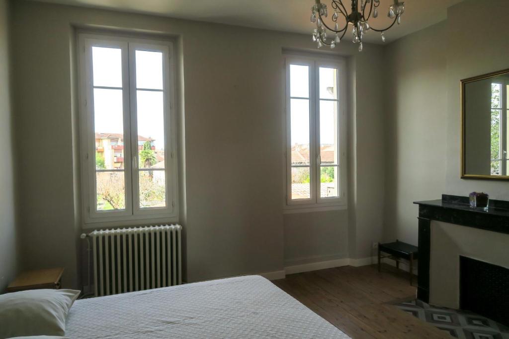 a bedroom with two windows and a bed and a fireplace at Chez Carmen in Albi