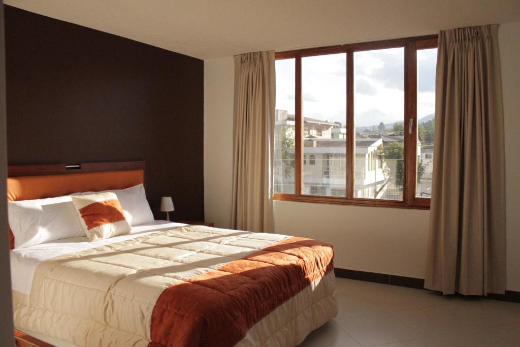 a bedroom with a bed and a large window at Hotel Casa Sakiwa in Machachi