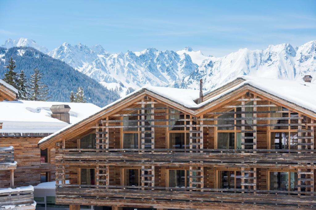 a log cabin with snow covered mountains in the background at W Verbier in Verbier