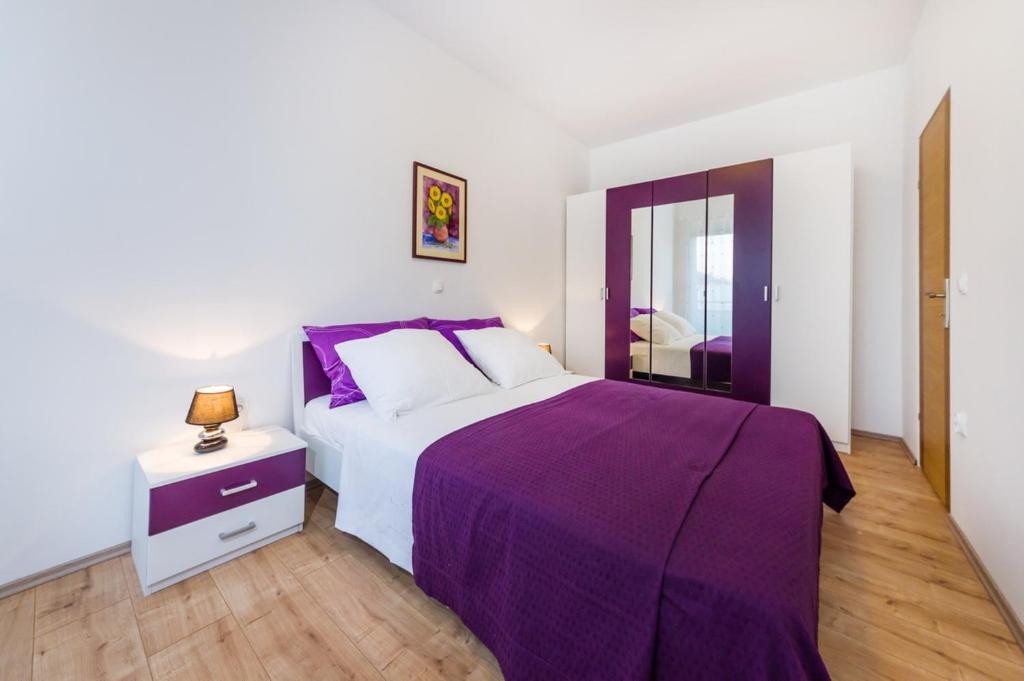 a bedroom with a purple bed and a night stand at Apartment Sara in Zadar
