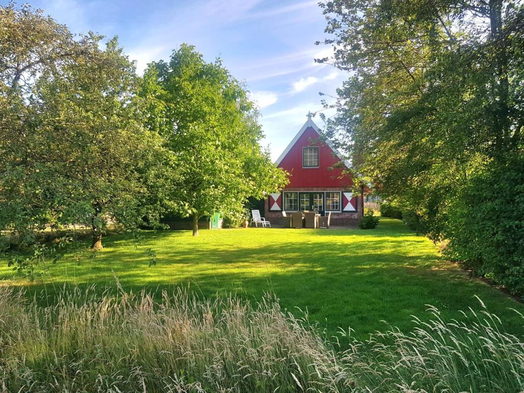 un granero rojo en medio de un patio verde en Huisje Weidezicht, en Lievelde