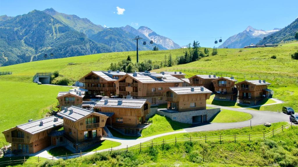 a group of houses on a hill with mountains in the background at Bergdorf Hotel Zaglgut in Kaprun
