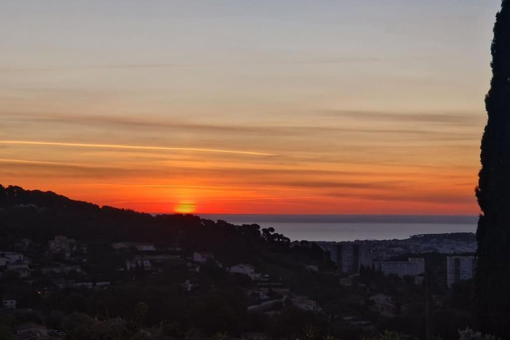 a sunset with the sun setting over a city at Beautiful Sea View House in Vallauris