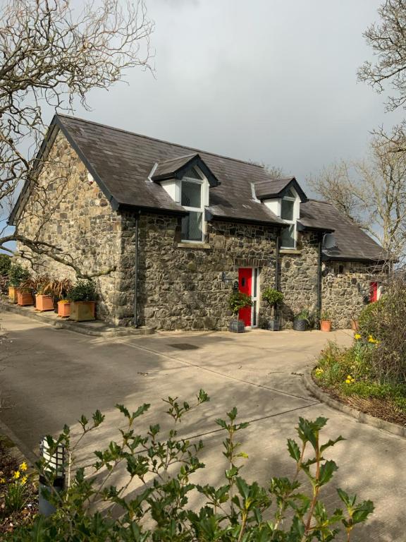 a stone house with a red door on a driveway at The Barn at BallyCairn in Larne