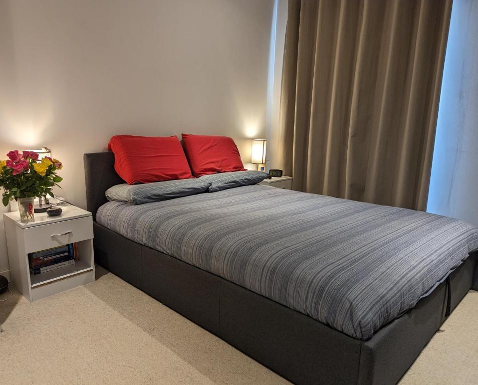 a bedroom with a bed with two red pillows on it at Luxury One Bedroom Flat in Deptford in London