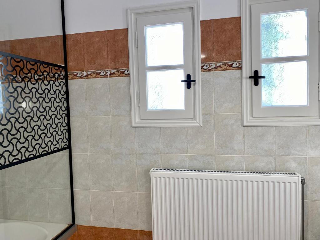 a bathroom with a radiator and two windows at PORTA HOME modern and hospitable in Naxos Chora