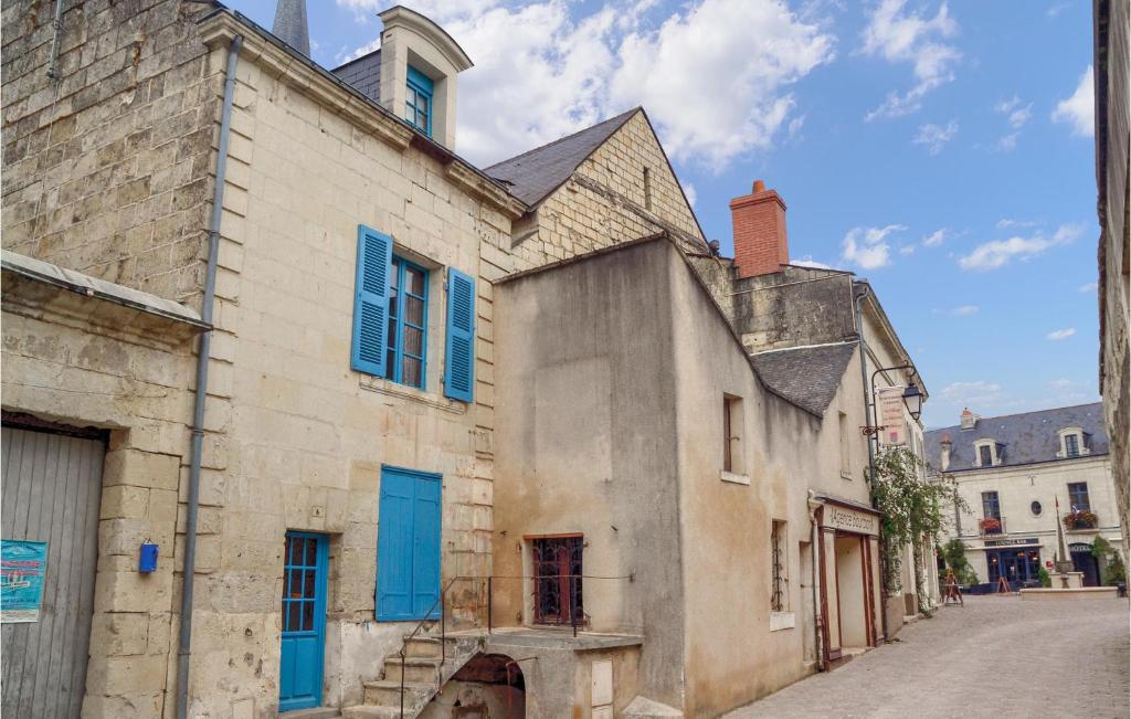 un vieux bâtiment avec volets bleus dans une rue dans l'établissement Amazing Home In Fontevraud Labbaye With Wifi, à Fontevraud-l'Abbaye