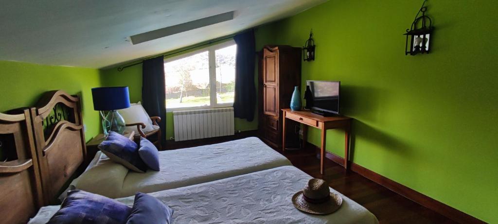 a green room with two beds and a television at casa rural usko in Amurrio
