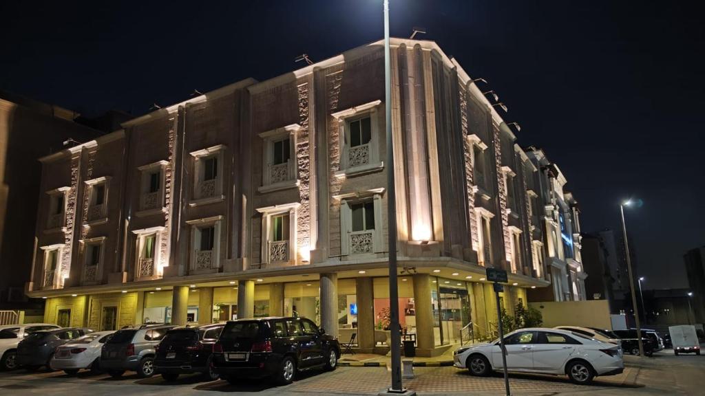 ein großes Gebäude mit Autos auf einem Parkplatz in der Unterkunft Plaza Home in Khobar
