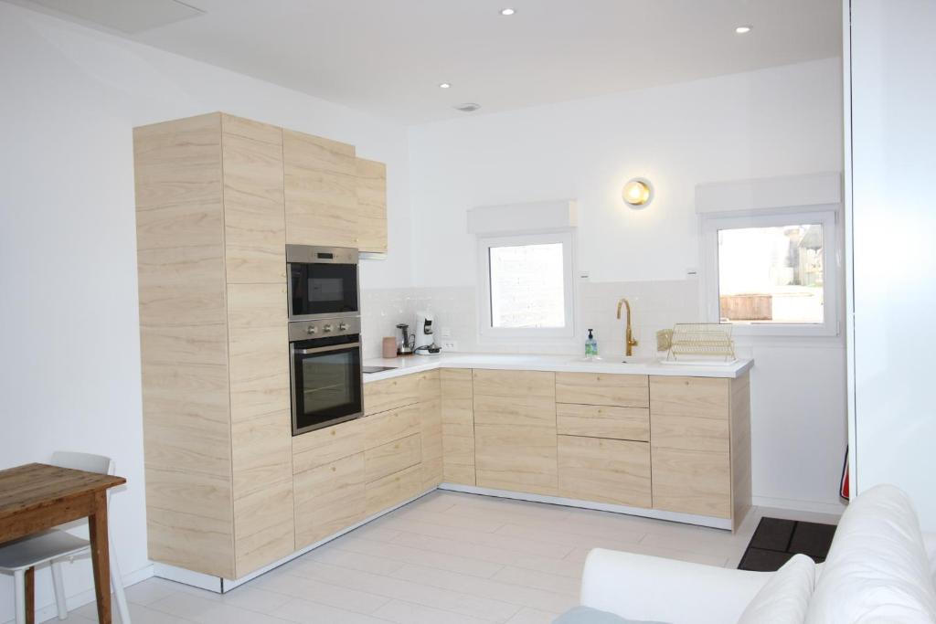 cocina con paredes blancas y armarios de madera en Maisonnette centre de Saint Dizier, en Saint-Dizier