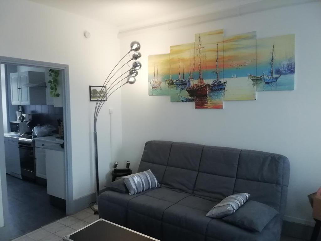 ein Wohnzimmer mit einem Sofa und einer Küche in der Unterkunft Pégase meublé 3*** in Fourchambault