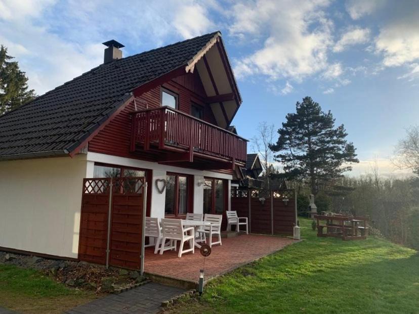 ein rotweißes Haus mit einer Terrasse und einem Tisch in der Unterkunft Ferienhaus Lisa am Silbersee in Frielendorf