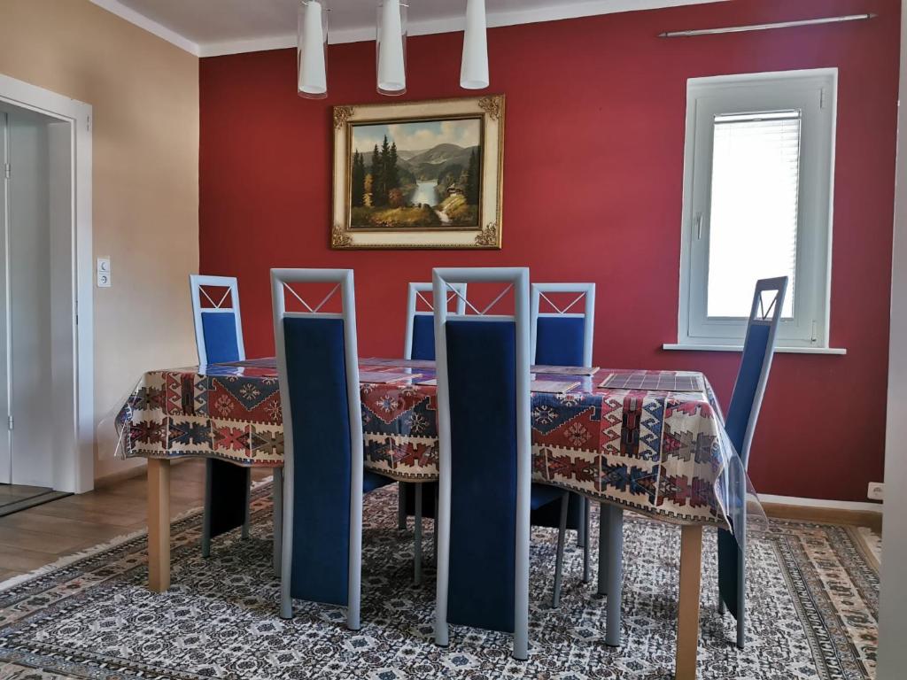 a dining room with red walls and a table with blue chairs at Shiraz-Home Ferienhaus in Holzminden an der Weser in Holzminden