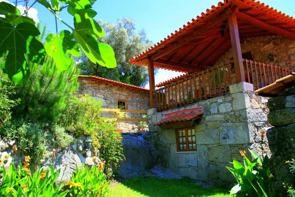 a stone house with a wooden roof on a yard at Casa Da Rocha in Caldelas