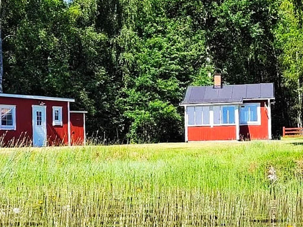 a small house in a field next to a forest at Holiday home GRIMSTORP in Grimstorp