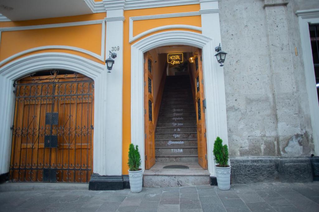 an orange and white building with stairs and two plants at Hostal TELSA SWEET STAY Inkahoteles in Arequipa