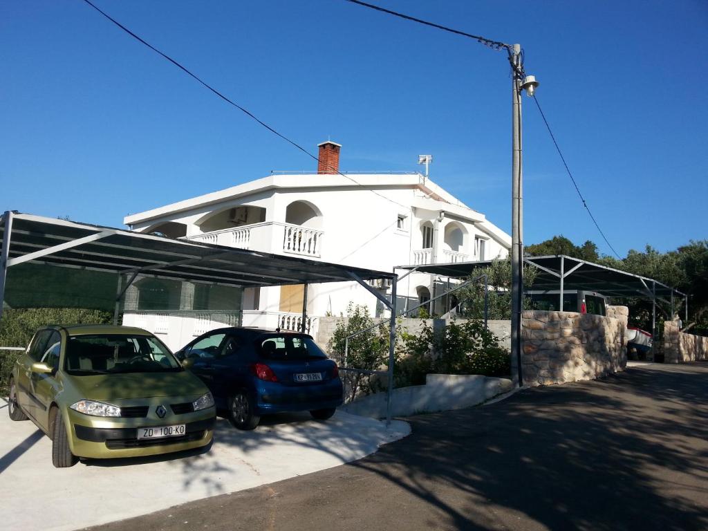 two cars parked in front of a white house at Apartmani Barbara in Vinjerac