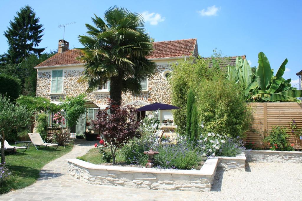 una casa con una palmera en un jardín en Chambres d'Hôtes Le Petit Nailly, en Magny-les-Hameaux