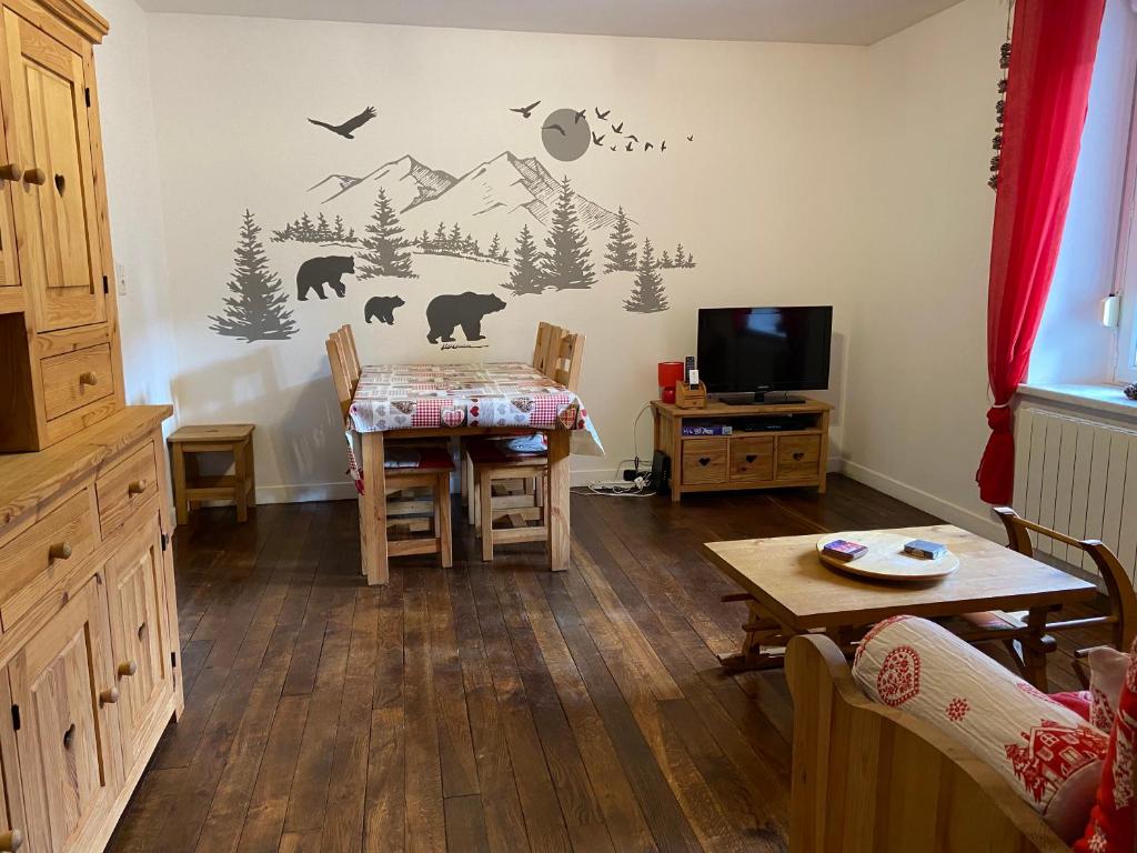 a living room with a table and a tv at Le Chellois appartement La Bresse in La Bresse