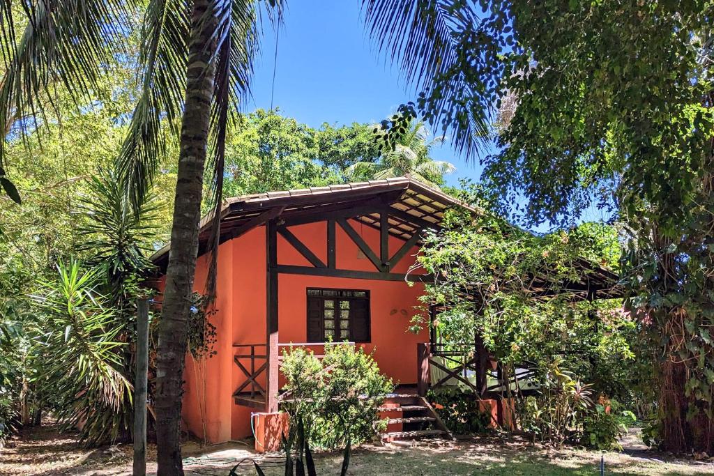 uma pequena casa vermelha no meio das árvores em Casa Vilacentro - Imbassaí em Imbassaí