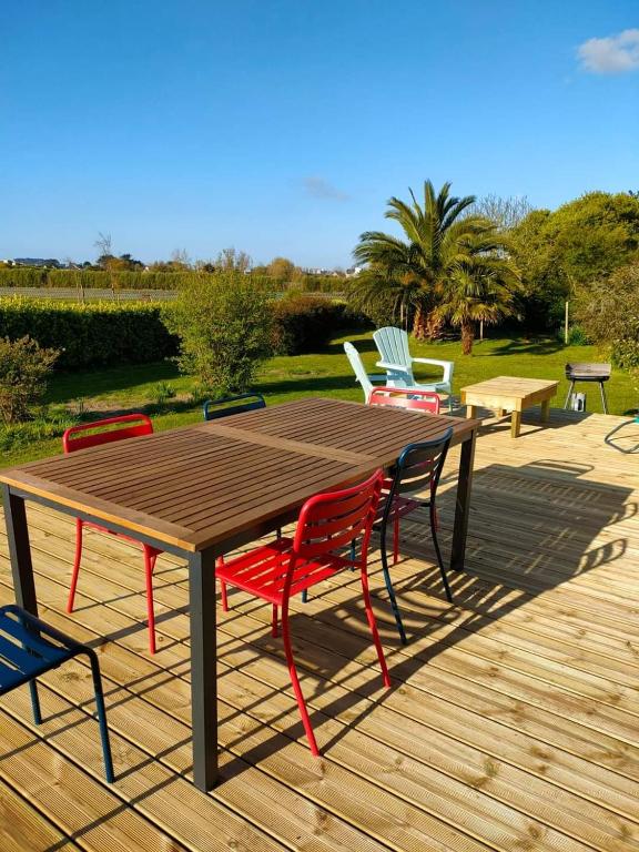a wooden table and chairs on a wooden deck at Calme et lumière à 2 pas de la mer in Plouescat