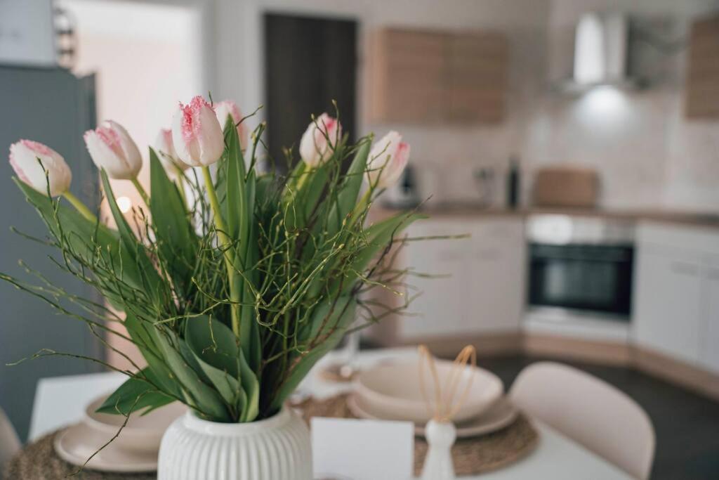 un jarrón con flores rosas sobre una mesa en una cocina en Gemütliche Wohnung nahe Kurpark, en Bad Lippspringe