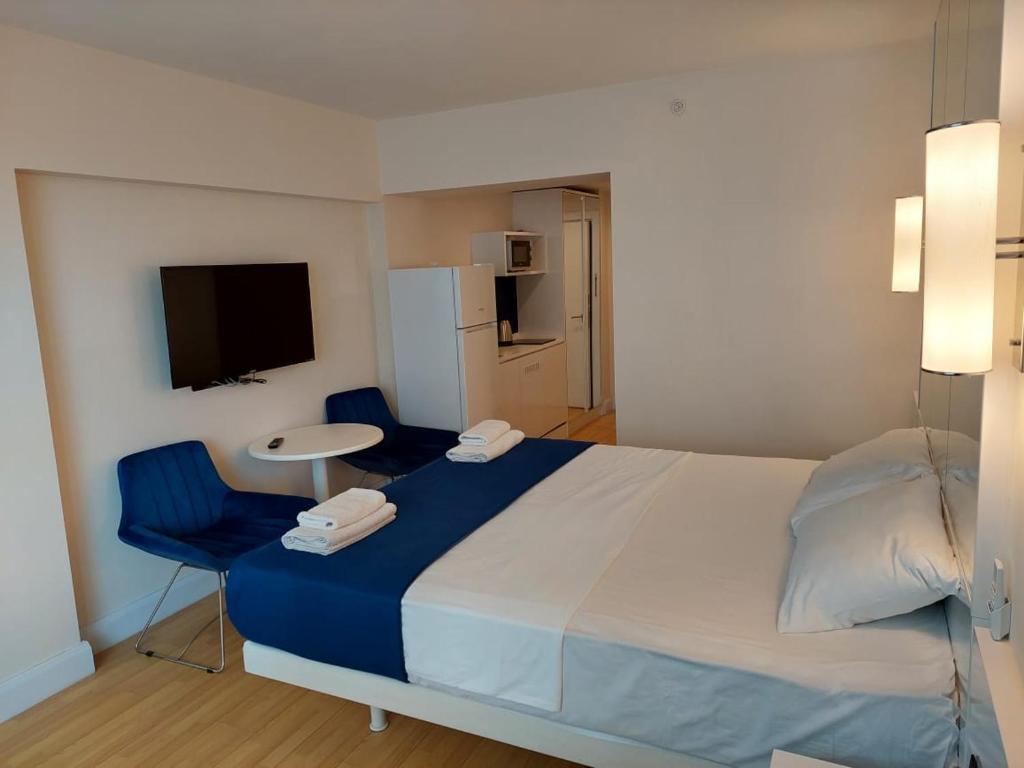 a bedroom with a bed and two chairs and a television at lux apartments orbi city in Angisa