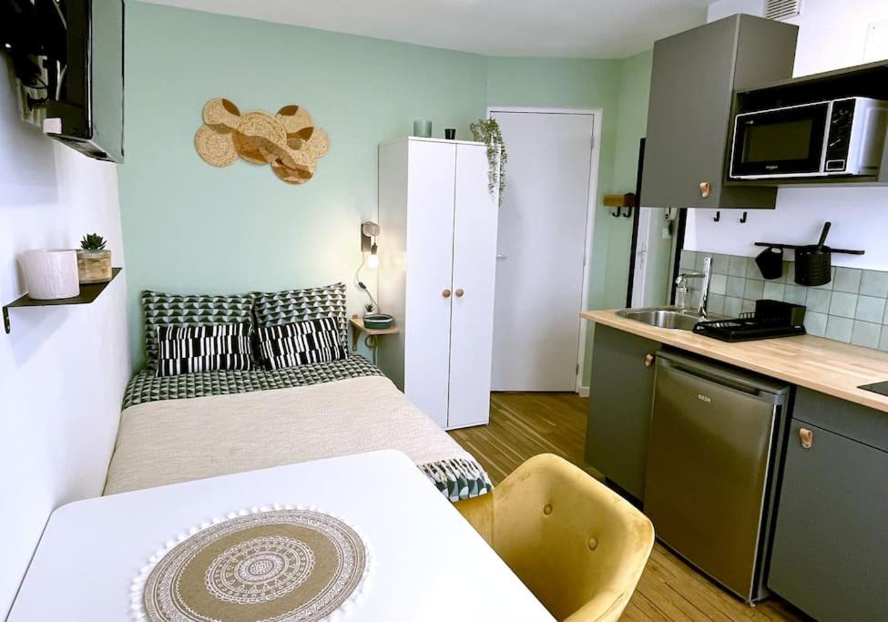 une petite chambre avec deux lits et une cuisine dans l'établissement Le Central • Hyper Centre • Proche Gare • Fibre, à Châteauroux