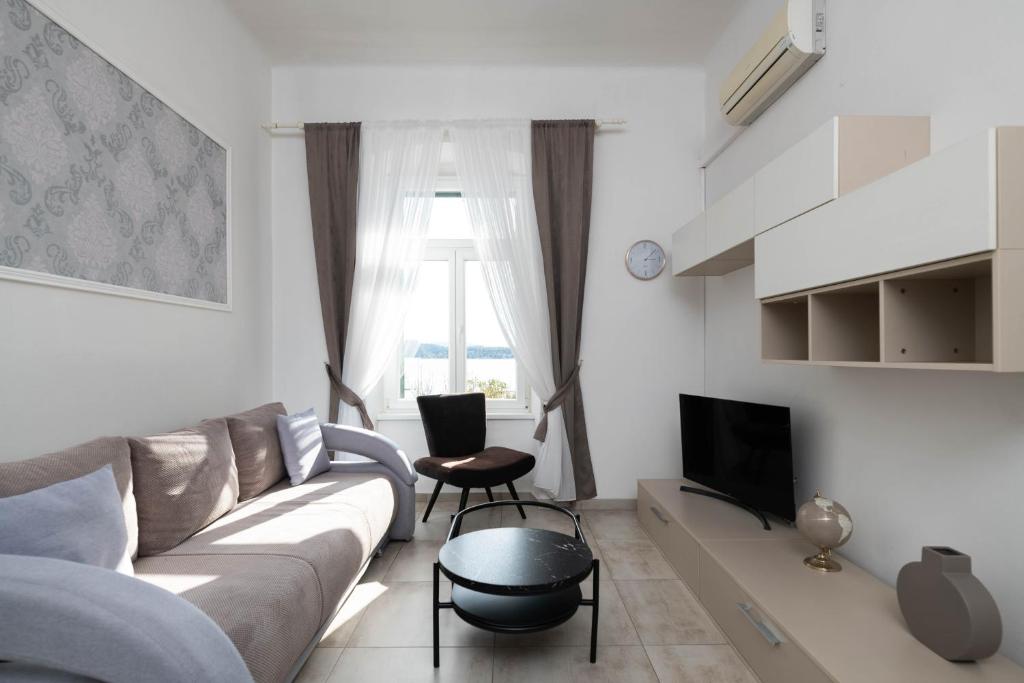 a living room with a couch and a tv at Apartment Val with sea view in Šibenik