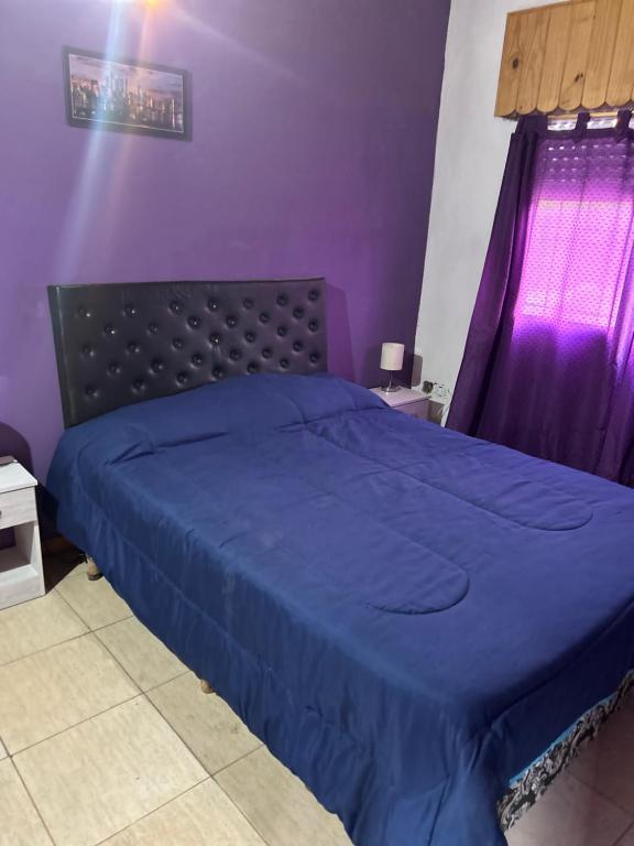 a purple bedroom with a bed with a blue comforter at Liza’s House Ezeiza Airport in Monte Grande