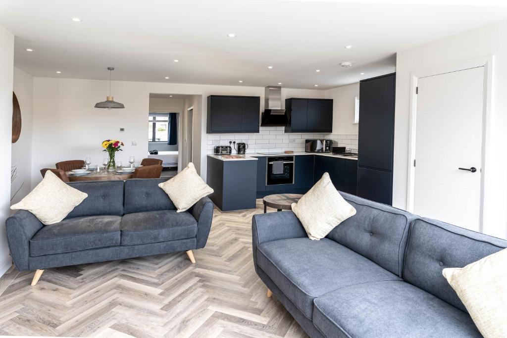 uma sala de estar com dois sofás azuis e uma cozinha em Modern new build, Close to the beach and town em Bude