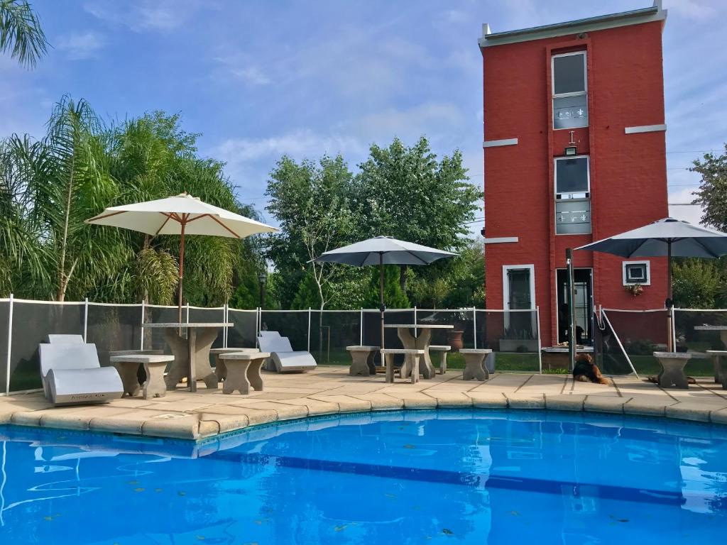 una piscina con mesas, sillas y sombrillas junto a un edificio en Bendito Alcázar Cabañas en Colón