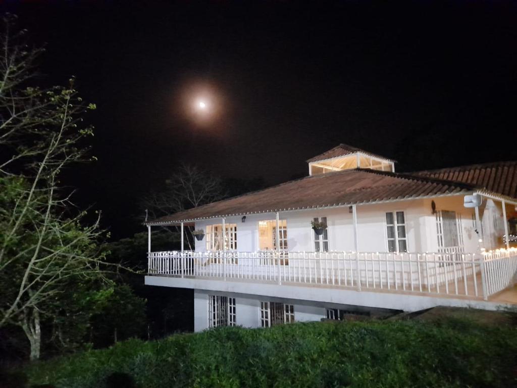 een wit huis 's nachts met de maan in de lucht bij Hotel Casa la Gregorienne in La Vega