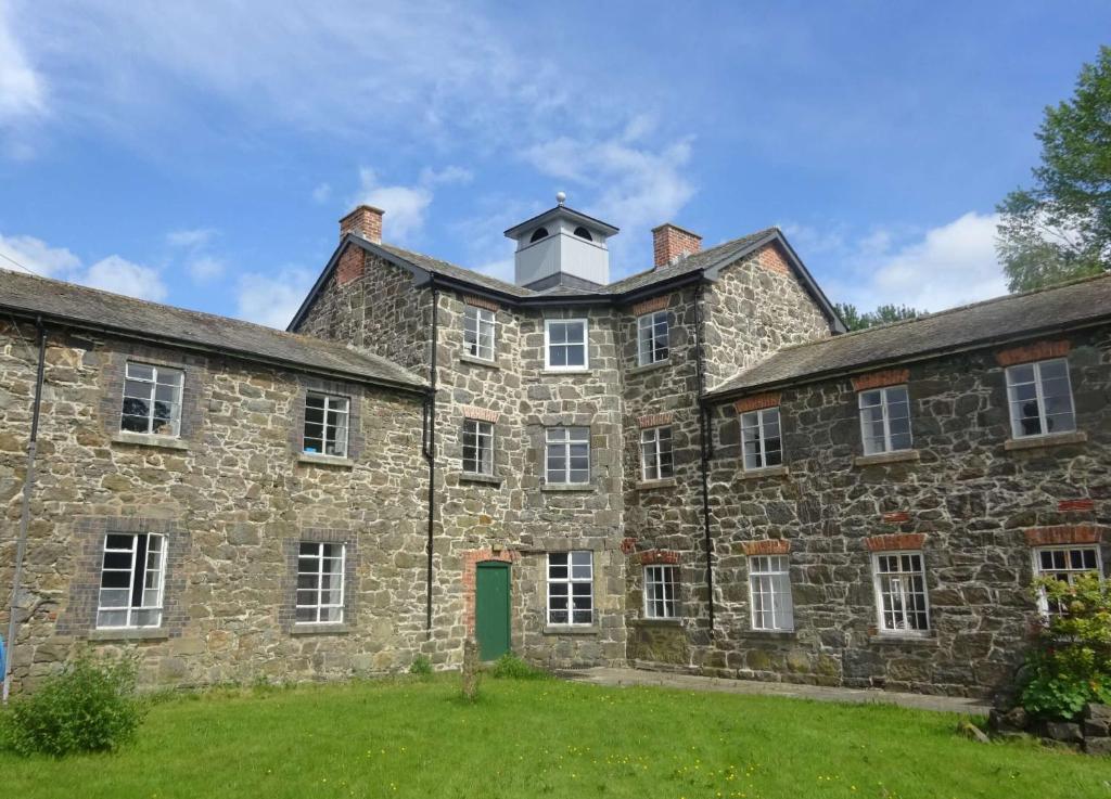 un vieux bâtiment en pierre avec une tour en haut dans l'établissement Llanfyllin Workhouse - Y Dolydd, à Llanfyllin
