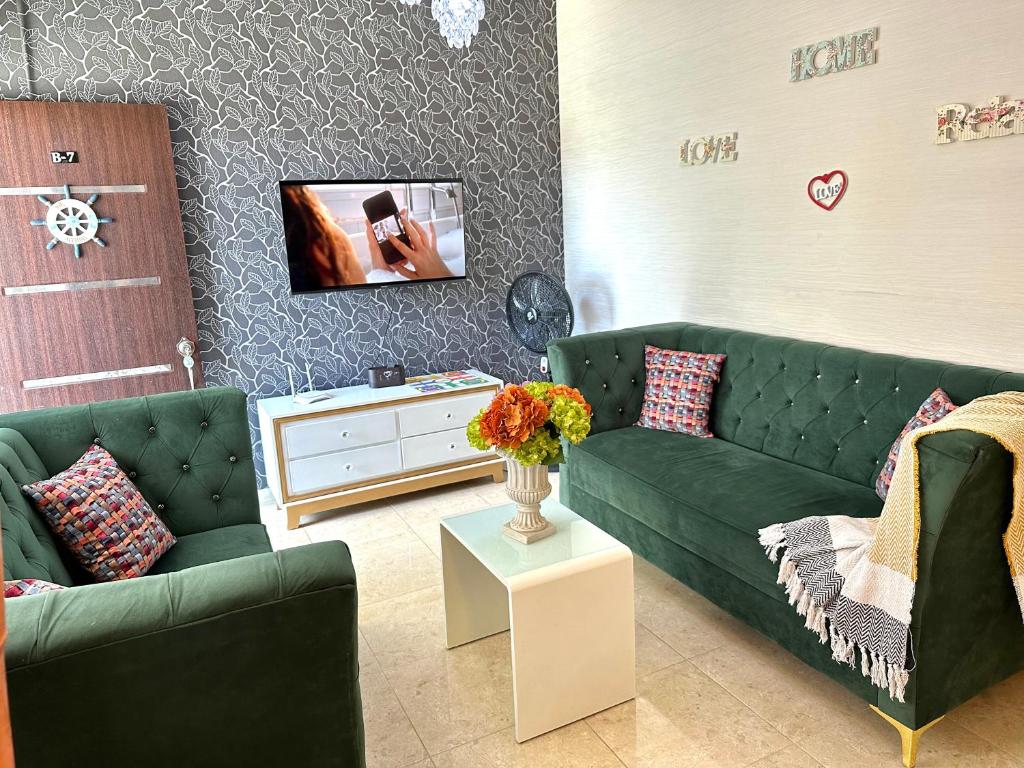 a living room with two green couches and a tv at B-7 hermoso apartamento zona de Parapentes al pie de la montaña in Jarabacoa