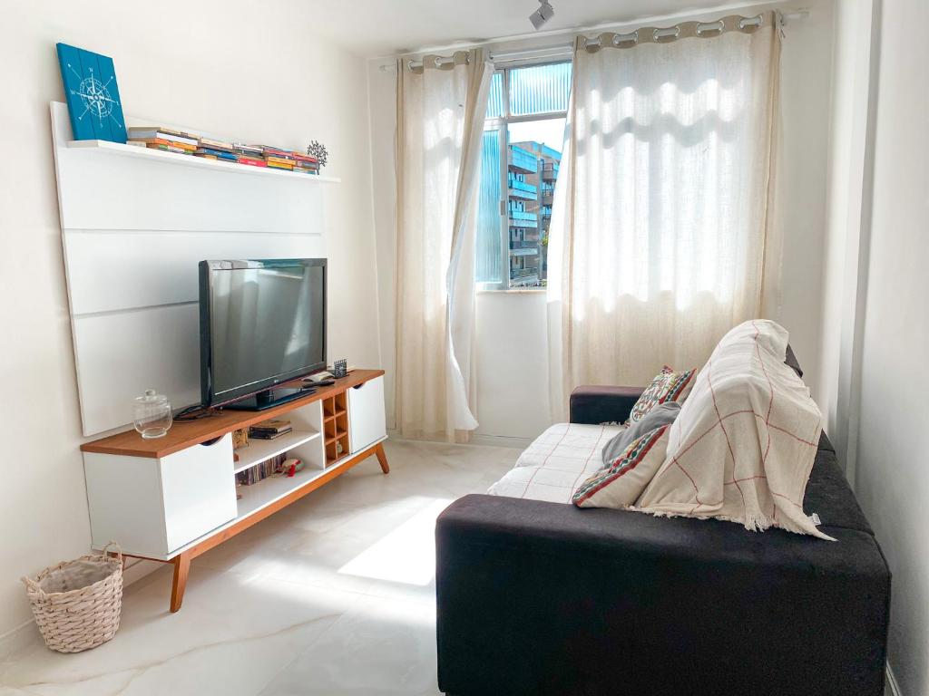 uma sala de estar com uma televisão e um sofá em Delicinha, a 5 minutos à pé da Praia do Forte em Cabo Frio