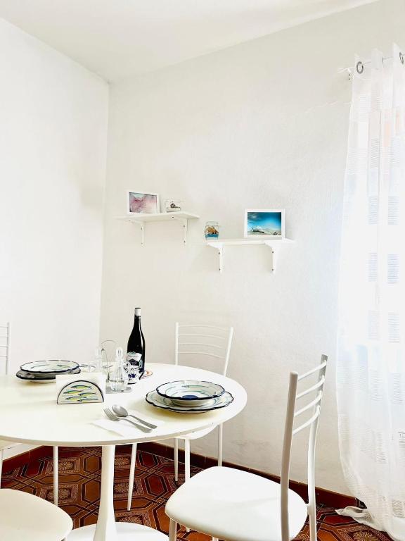 una sala da pranzo bianca con tavolo e sedie bianchi di Meridiana a Ischia