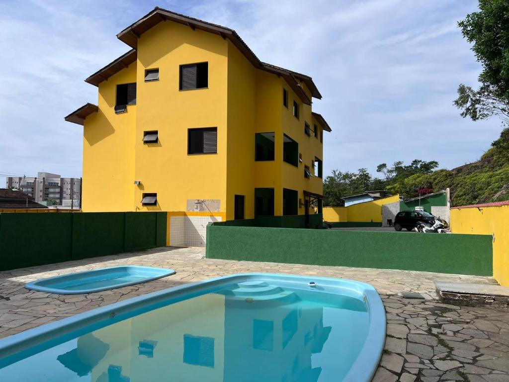 a yellow building and a swimming pool in front of a house at Apartamento Mar Brasil II in Ubatuba