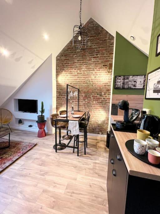 une cuisine avec une table et un mur en briques dans l'établissement Le Central 3 - Pépite en centre ville d’Elbeuf, à Elbeuf