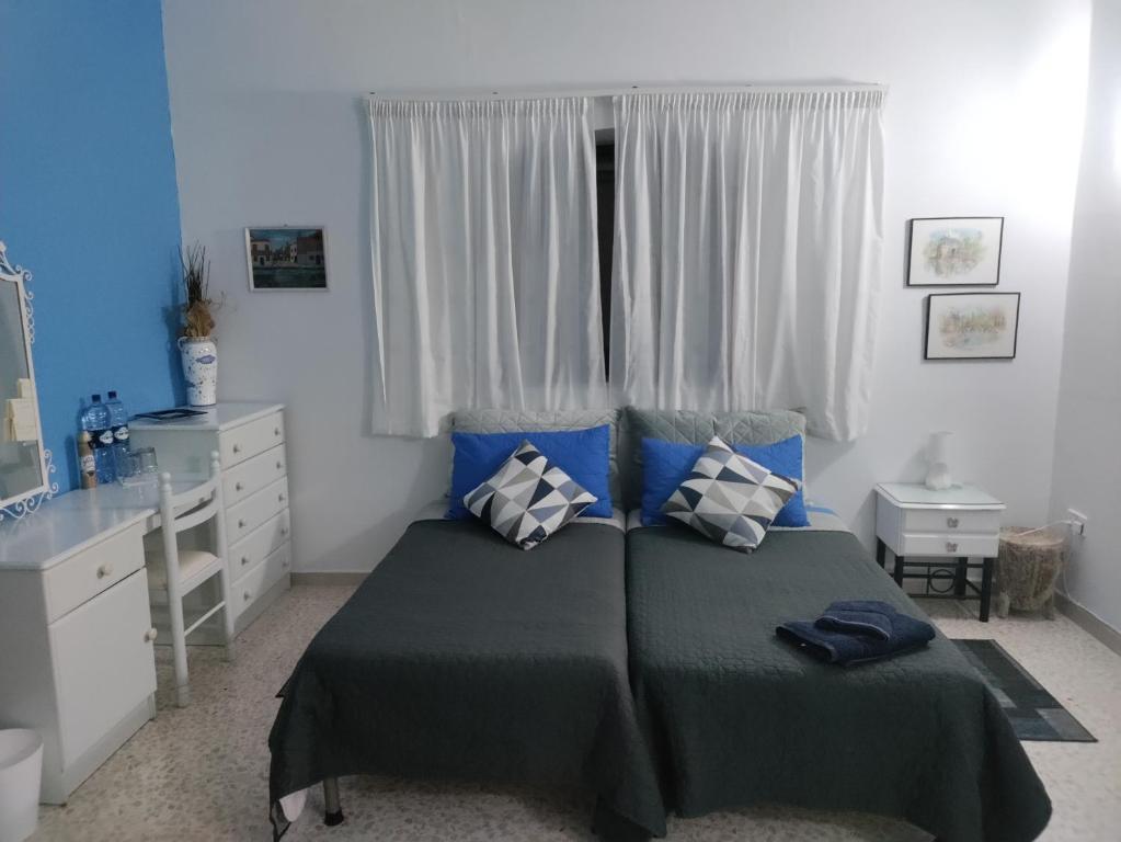 Un dormitorio con una cama con almohadas azules y una ventana en Homestay Naxxar en Naxxar