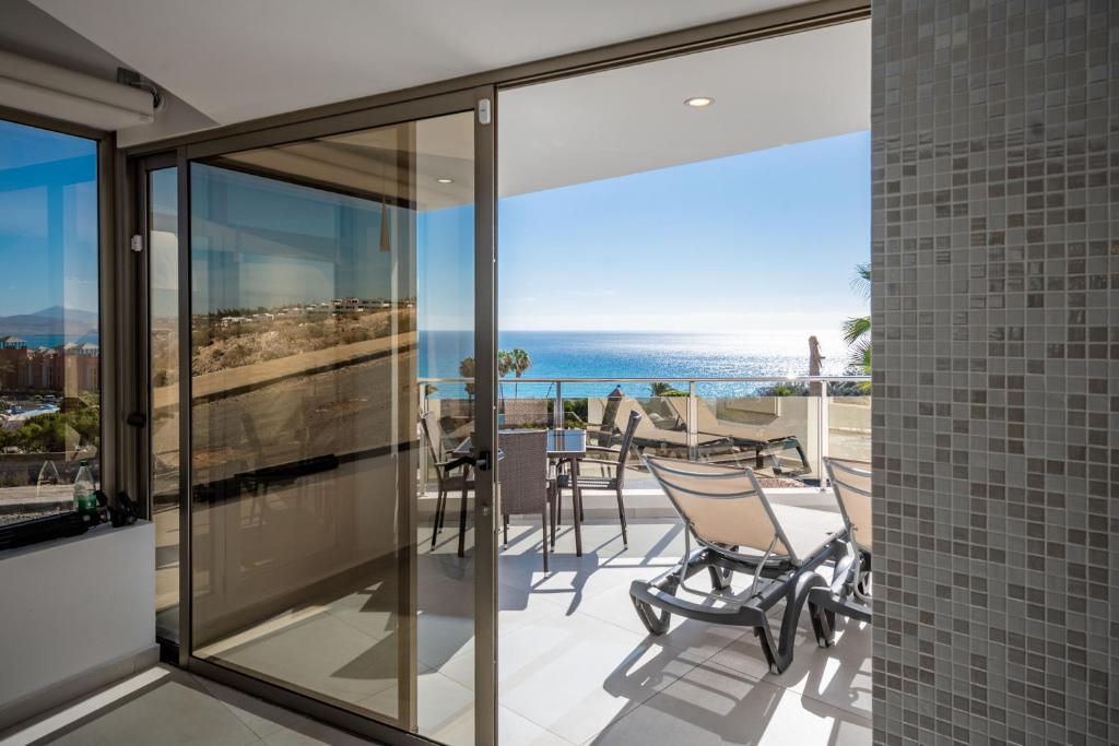 een balkon met glazen deuren en uitzicht op de oceaan bij Villa Selene heated Indoor Pool in Costa Calma