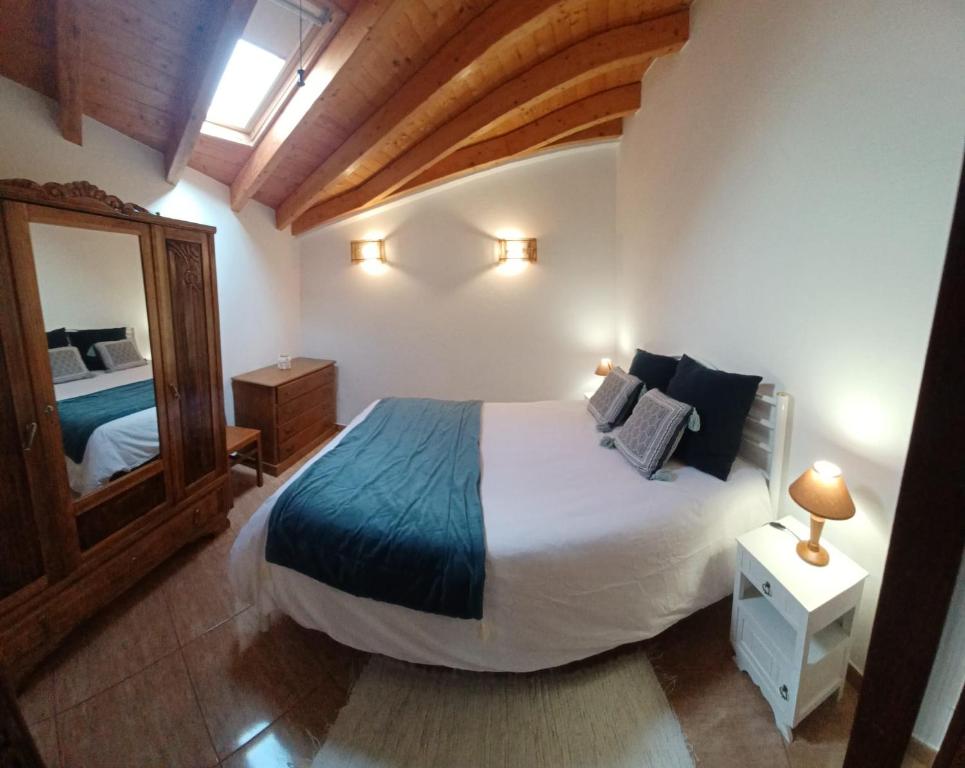 a bedroom with a large bed and a mirror at O Refúgio dos Pais in Bordeira