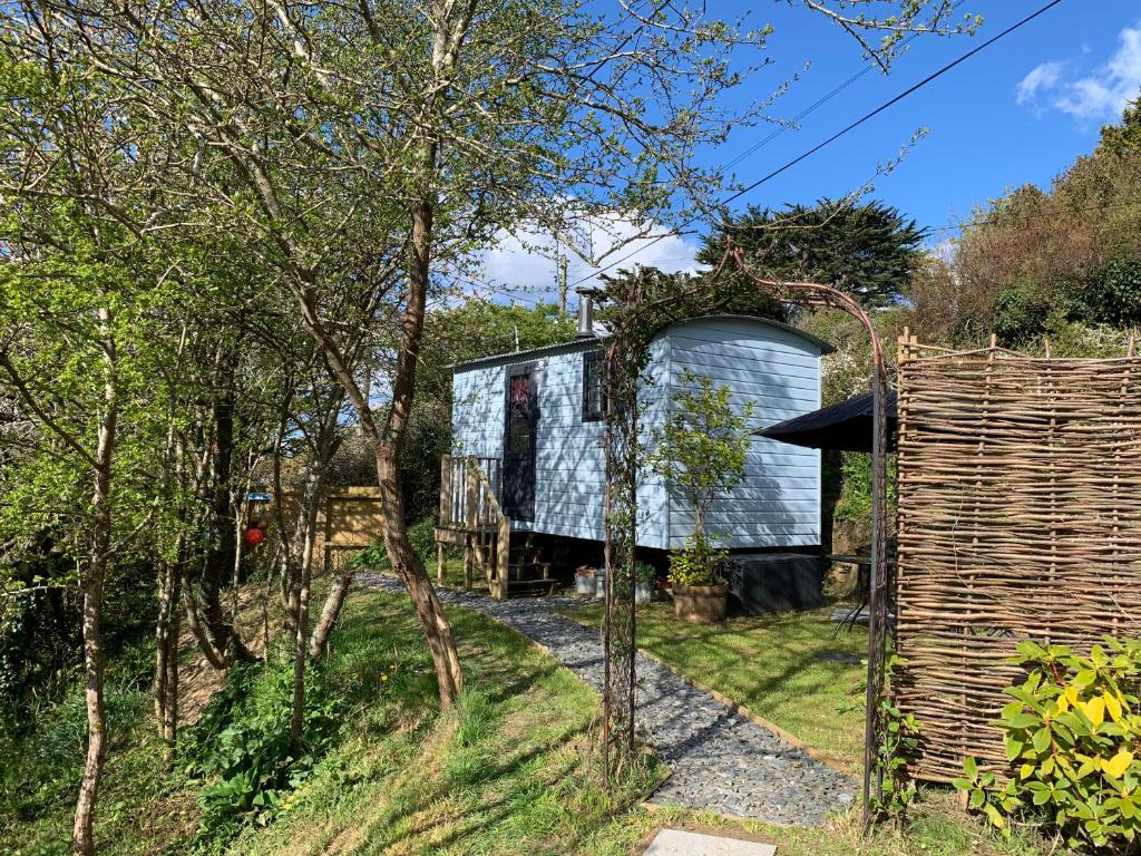 a tiny house in the middle of a garden at Tides Reach, Deluxe Shepherds hut, 100m from the Beach in St Merryn